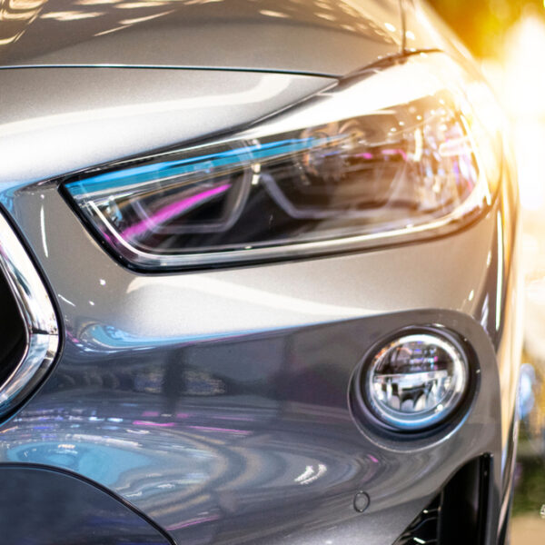 Modern, shiny SUV headlight in a car showroom.
