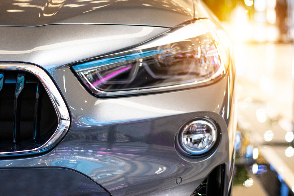 Modern, shiny SUV headlight in a car showroom.