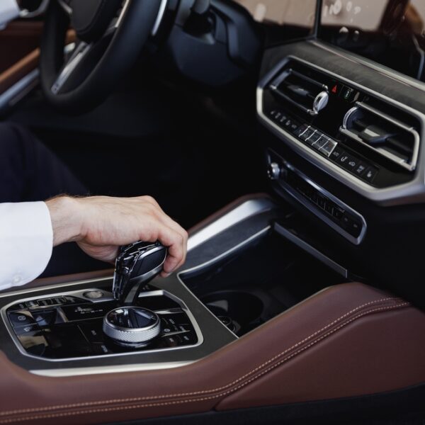 Close up cropped up photo shot hands european businessman man wearing white shirt sitting in car salon driving changes gears hold steering wheel automobile modern vehicle. Car sales driver concept.